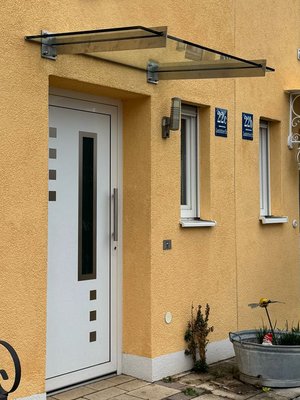 Glasvordach mit Edelstahlschwertern, montiert an Fassade mit Wärmedämmung