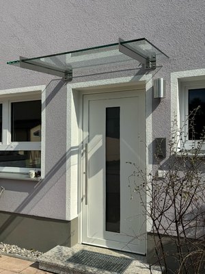 Glasvordach mit Edelstahlschwertern, montiert an Fassade mit Wärmedämmung